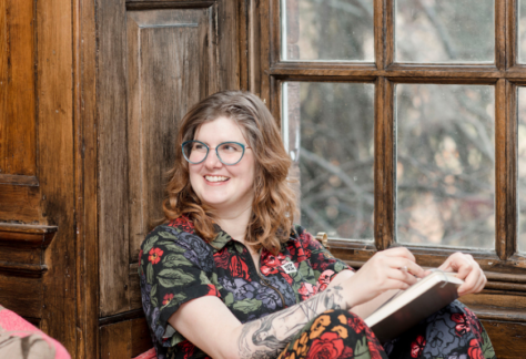 Sarah Wedderburn Ogilvy smiles as she reclines with a book in her lap.